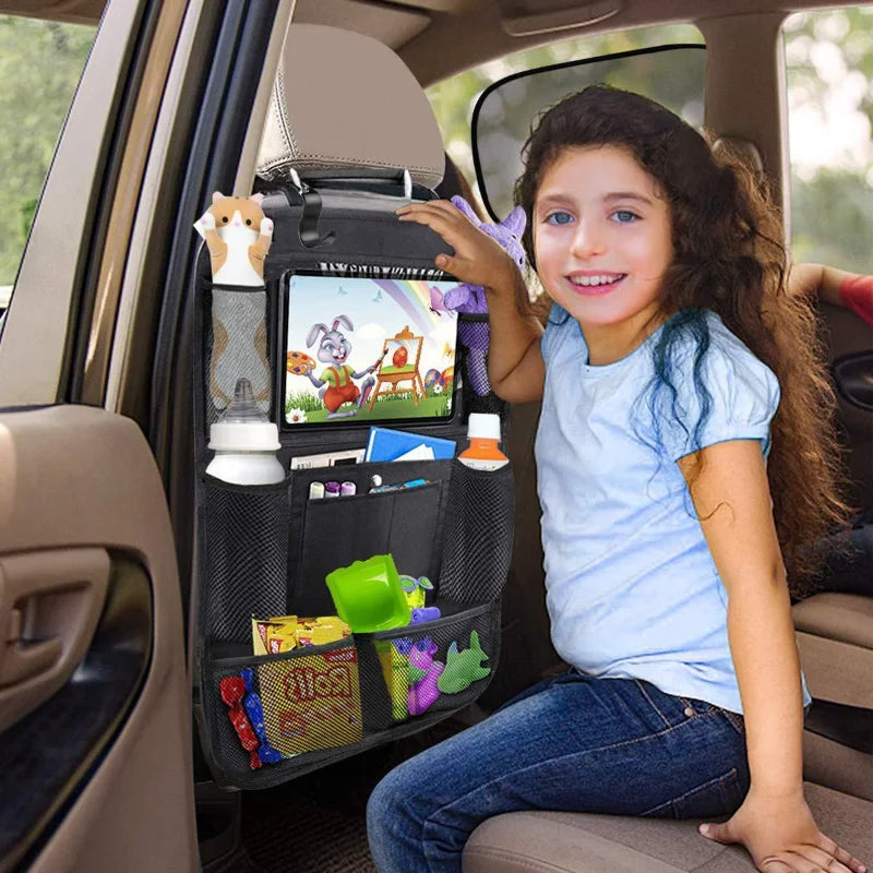 Child sitting in a car with a backseat organizer displaying toys and a tablet.