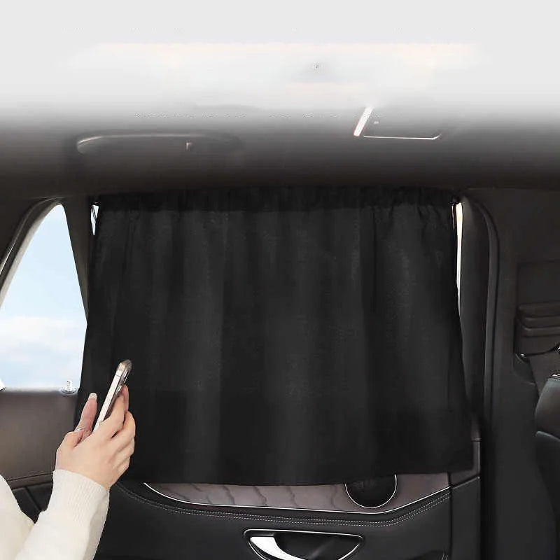 Car interior with a black curtain covering the window, person holding a phone.