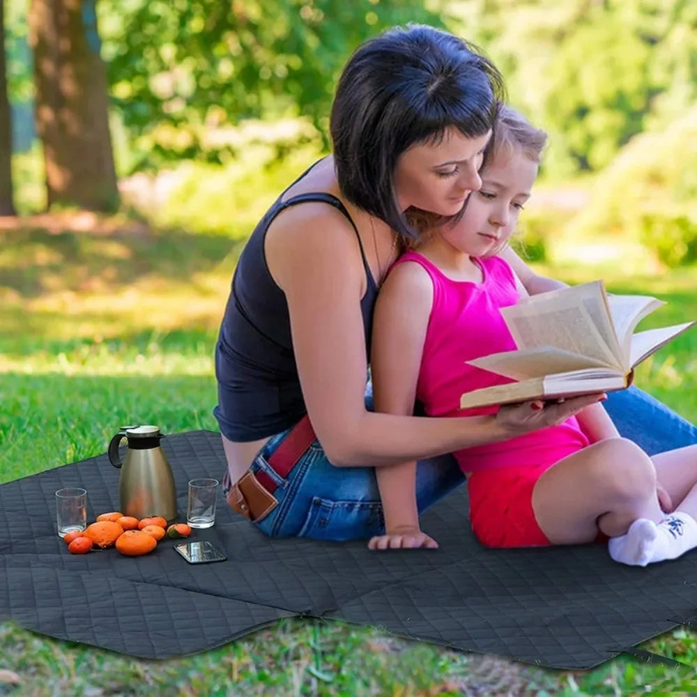 Woman and child reading a book on a picnic blanket in a park