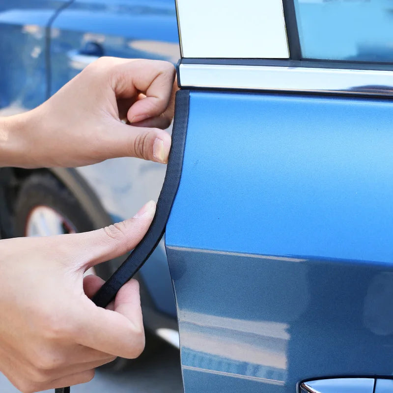 Person applying car wrap film to a blue car